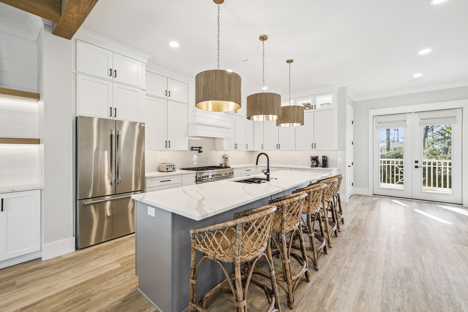 Step into your gourmet kitchen with gleaming marble countertops and warm woven barstools where morning coffee feels luxurious.