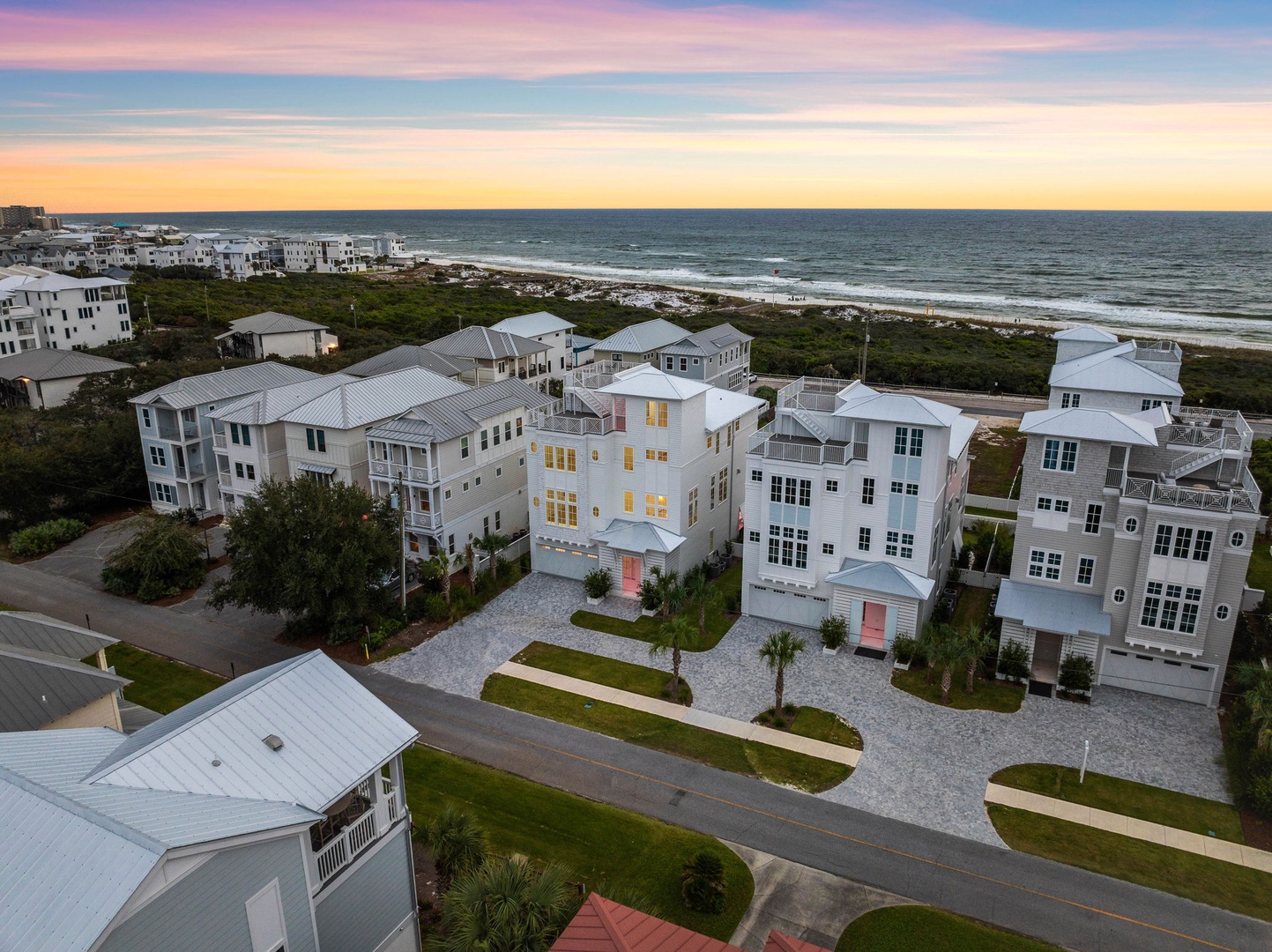Coastal community with modern beach houses overlooking pristine shores during golden hour.