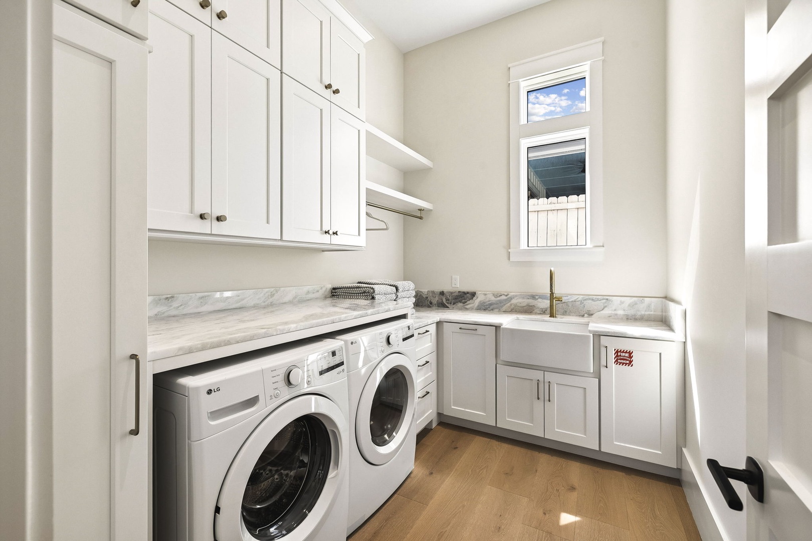 Your stylish laundry room combines form and function with gleaming white cabinetry, elegant marble countertops, and side-by-side washer-dryer units that make chore time a breeze.