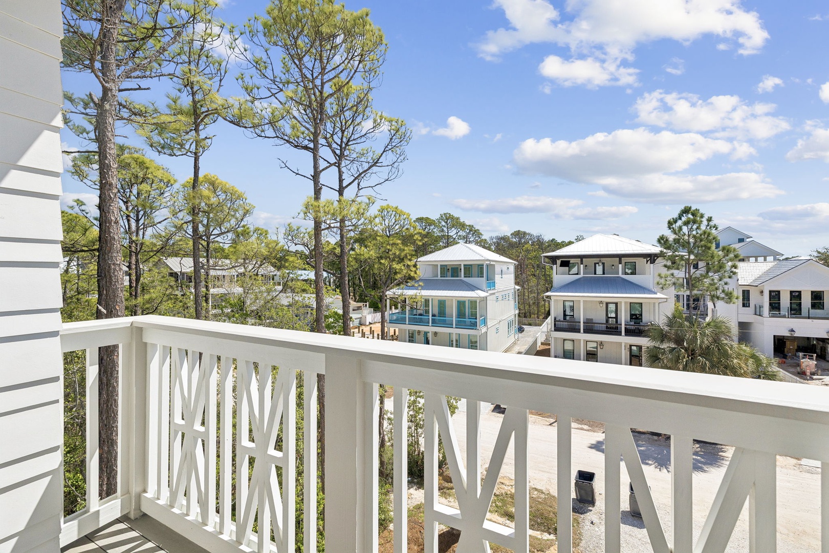 Step onto your private balcony and soak in peaceful views of coastal homes nestled among towering pines under endless blue skies.