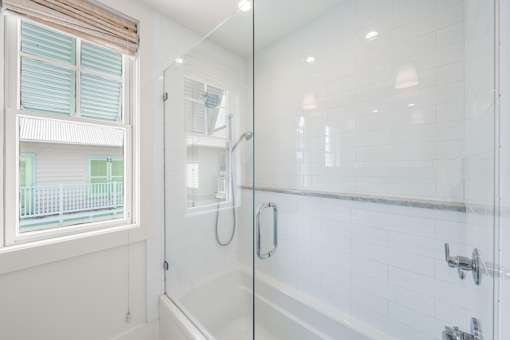 Soak in your spa-like bathroom featuring a luxurious glass-enclosed tub with elegant marble accents and bright natural light.