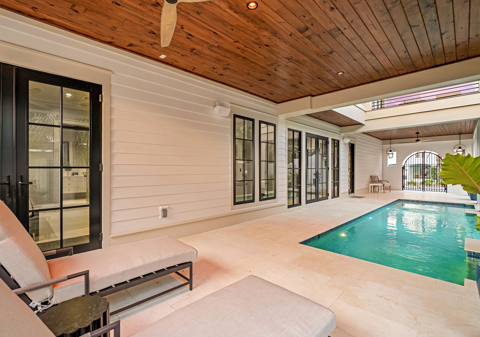 Your private poolside retreat awaits with elegant covered lounging, stunning wood ceiling details, and sparkling turquoise waters just steps away.