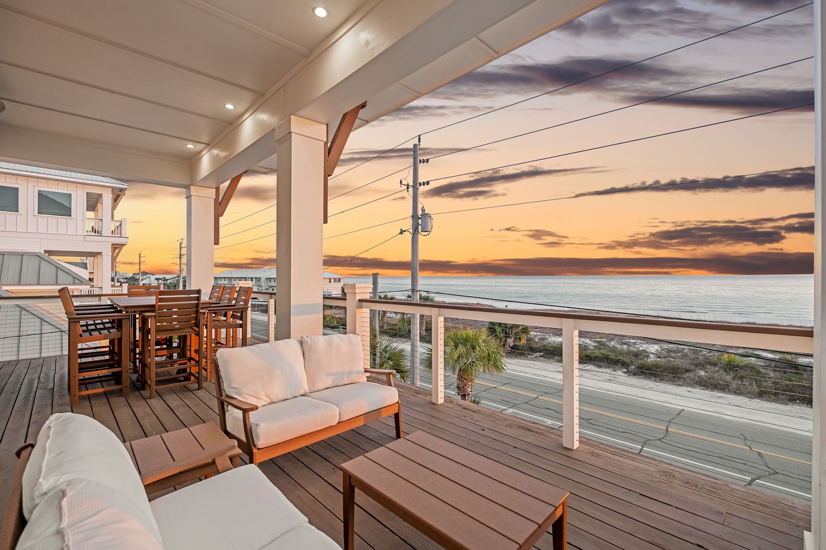 Stunning oceanfront deck with comfortable seating overlooking a breathtaking sunset view across the water.