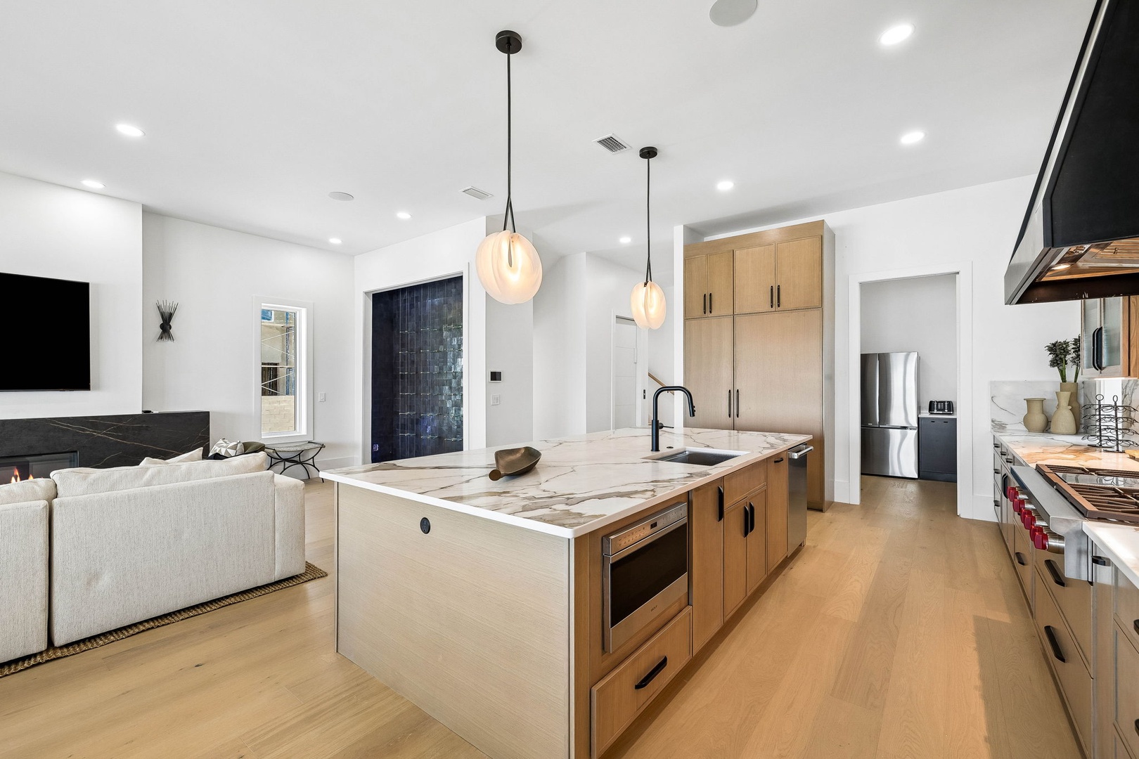 Step into a bright, modern space where the kitchen flows seamlessly into the living area. Warm wood tones and sleek marble surfaces invite you to cook, entertain, and unwind in style.