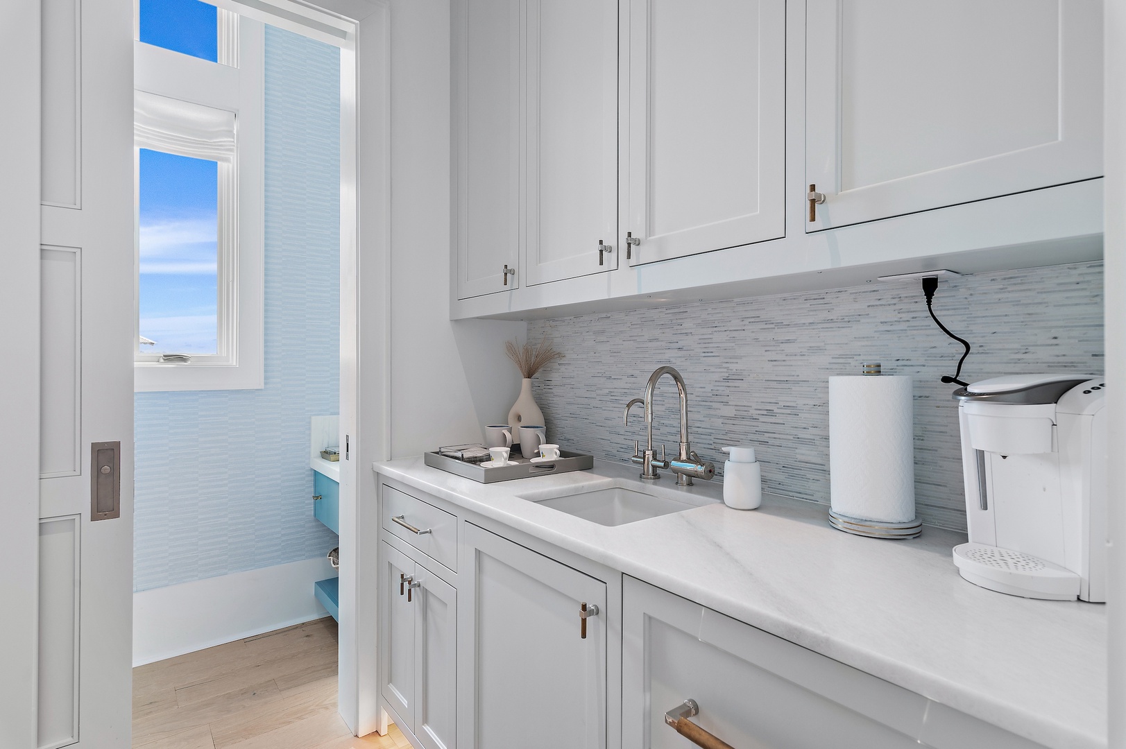 Step into your crisp, coastal-inspired kitchenette, where ocean views peek through the door and morning coffee becomes a tranquil ritual. Clean lines and beach-toned backsplash create a refreshing retreat.