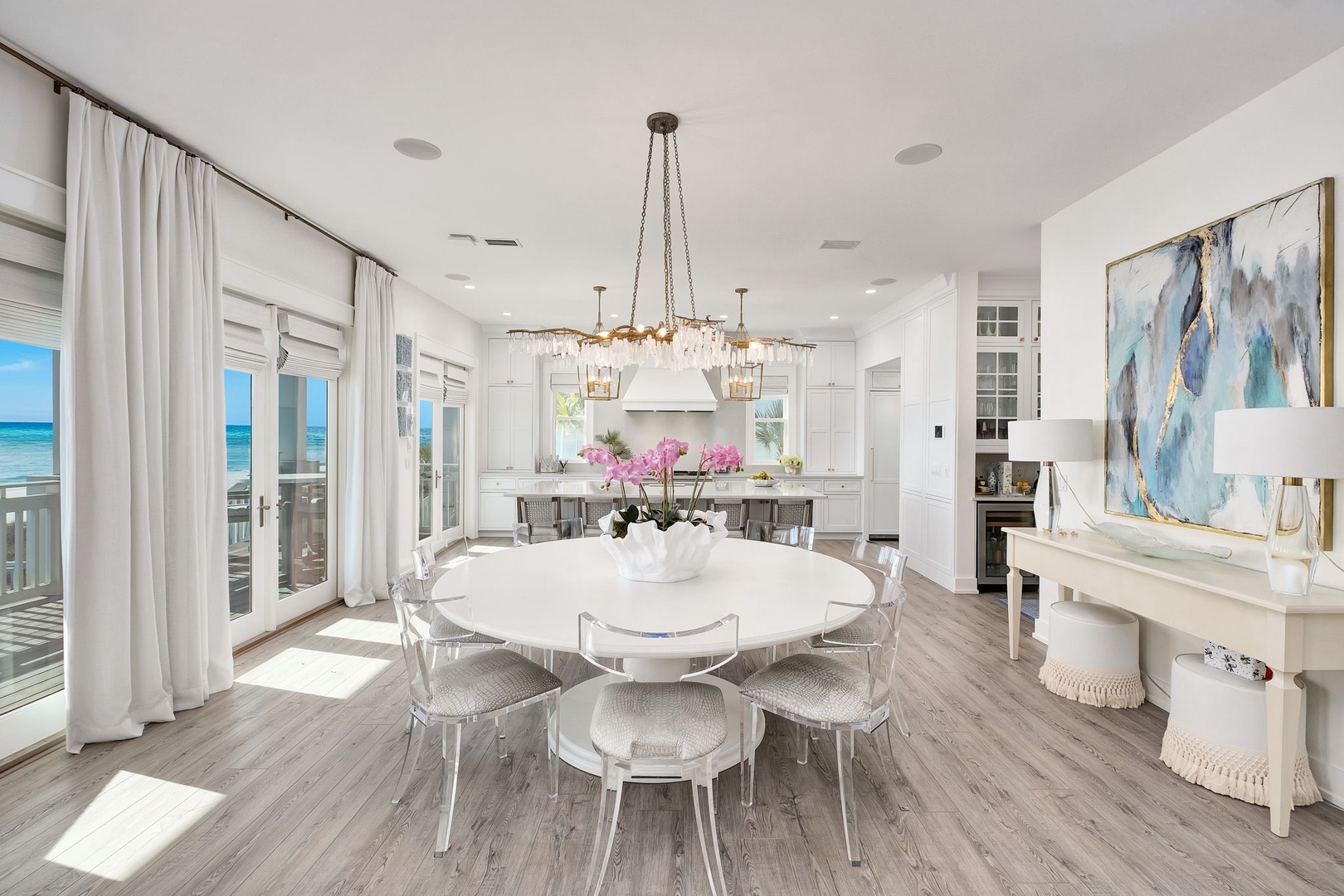 Bright, airy dining space flows seamlessly into a chef's kitchen, with ocean views just beyond the doors. Natural light pours in, highlighting elegant coastal details—perfect for memorable meals.