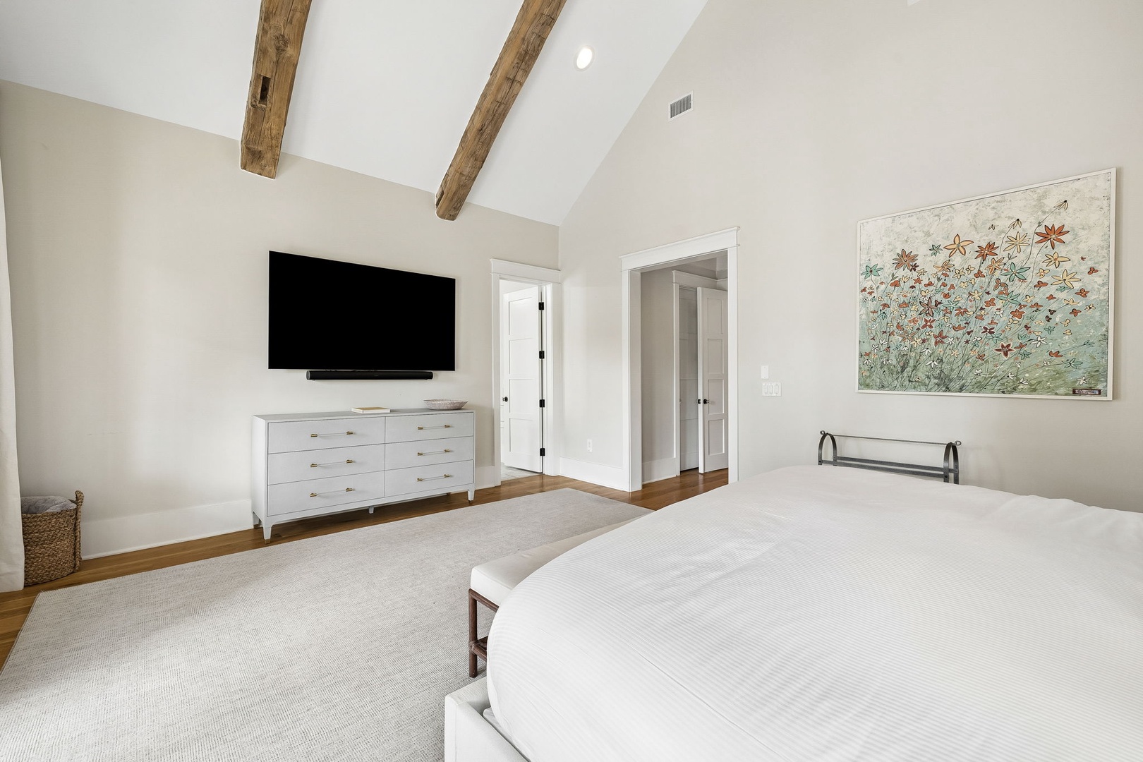 Sink into crisp white linens under soaring vaulted ceilings with rustic wood beams that bring warmth to your serene retreat.