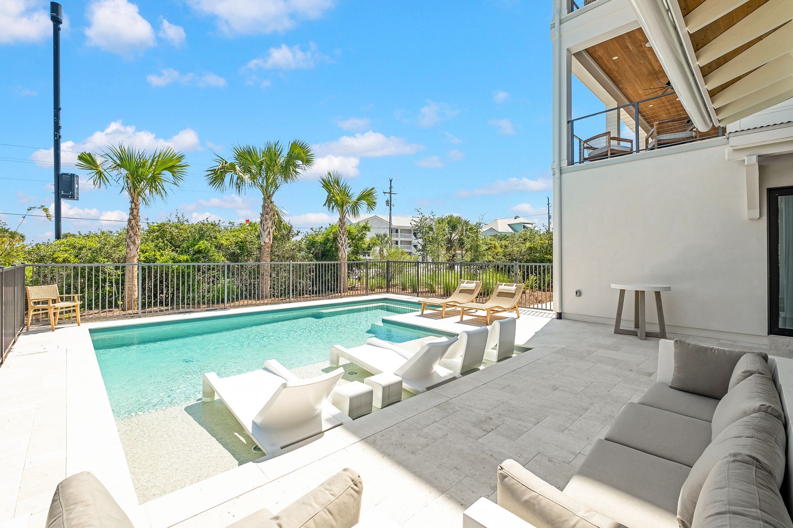 A modern coastal retreat featuring a private pool with attached spa, loungers for sunbathing, and tropical palm trees framing the property's landscaped surroundings.