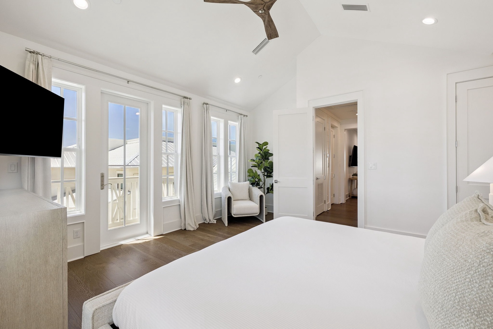 Sink into crisp white bedding and enjoy your private balcony access with serene views. The cozy reading chair awaits your morning coffee moments.