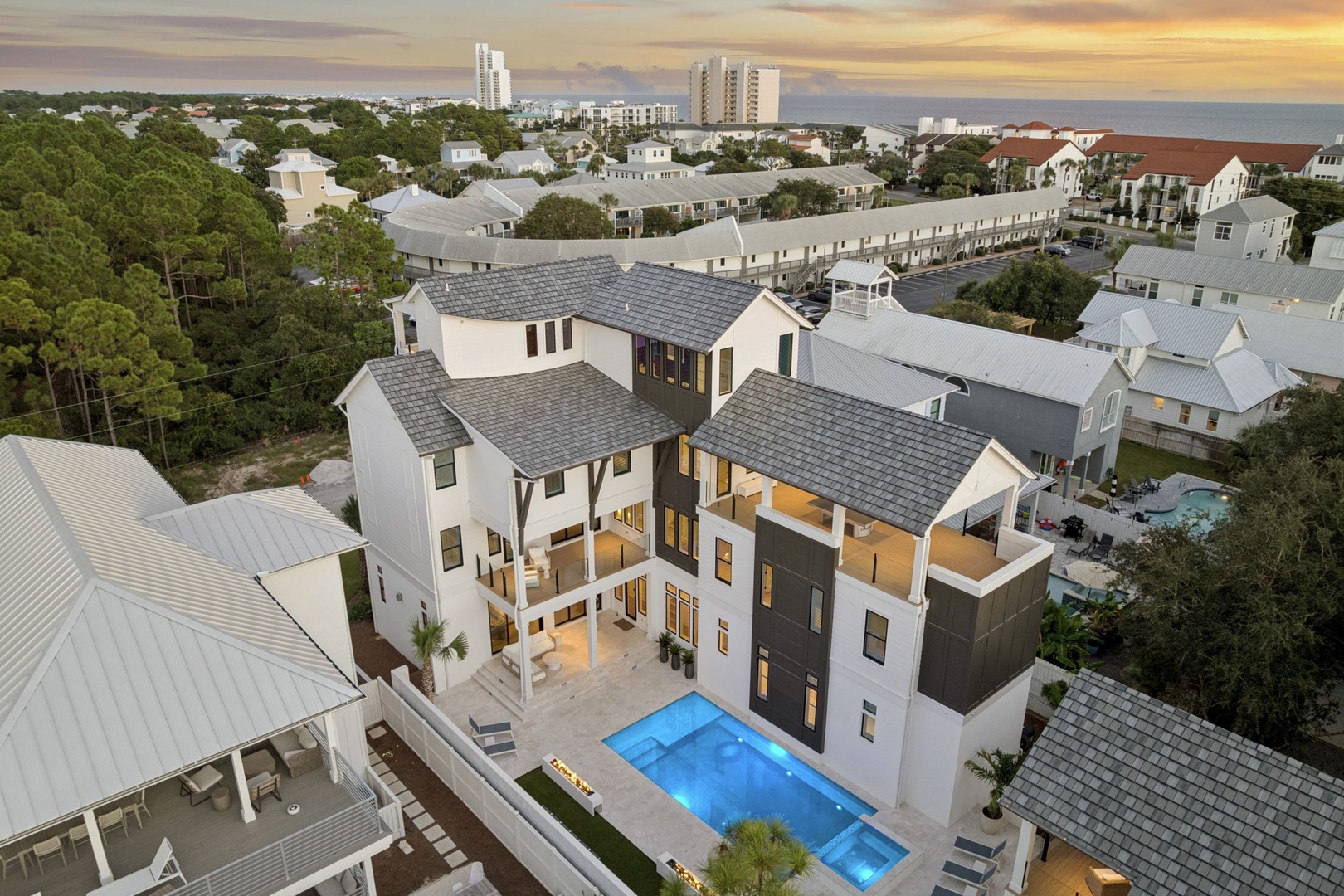 Aerial view of a modern coastal vacation home featuring a private pool, contemporary architecture, and a prime location near the beach and surrounding neighborhood.