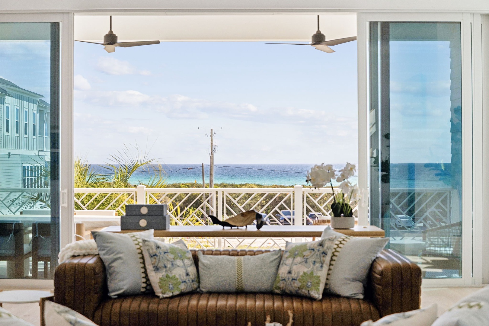 Your oceanfront living room opens to stunning sea views through floor-to-ceiling windows, where plush seating invites you to unwind with tropical breezes.
