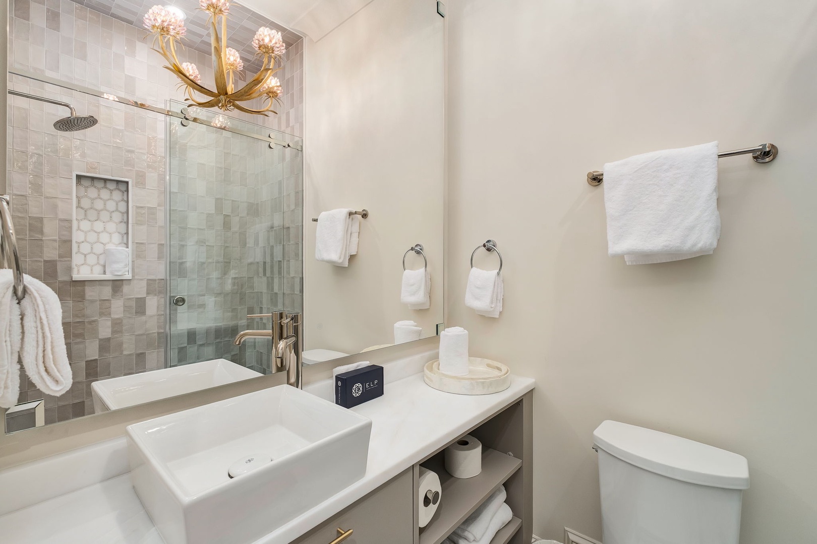 Step into your private spa-like retreat with elegant tilework, a rainfall shower, and plush towels awaiting your arrival. The custom lighting and modern finishes create a serene escape for your morning routine.