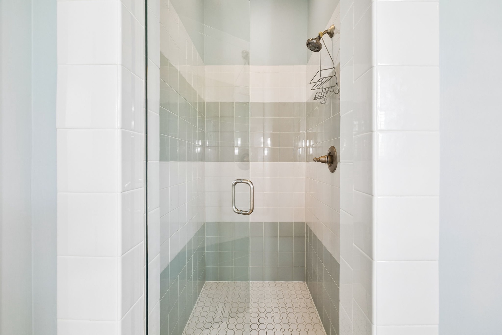 Step into your spa-like walk-in shower, where soothing seafoam tiles meet gleaming brass fixtures. The spacious enclosure and rainfall showerhead invite you to unwind after a day of adventure.