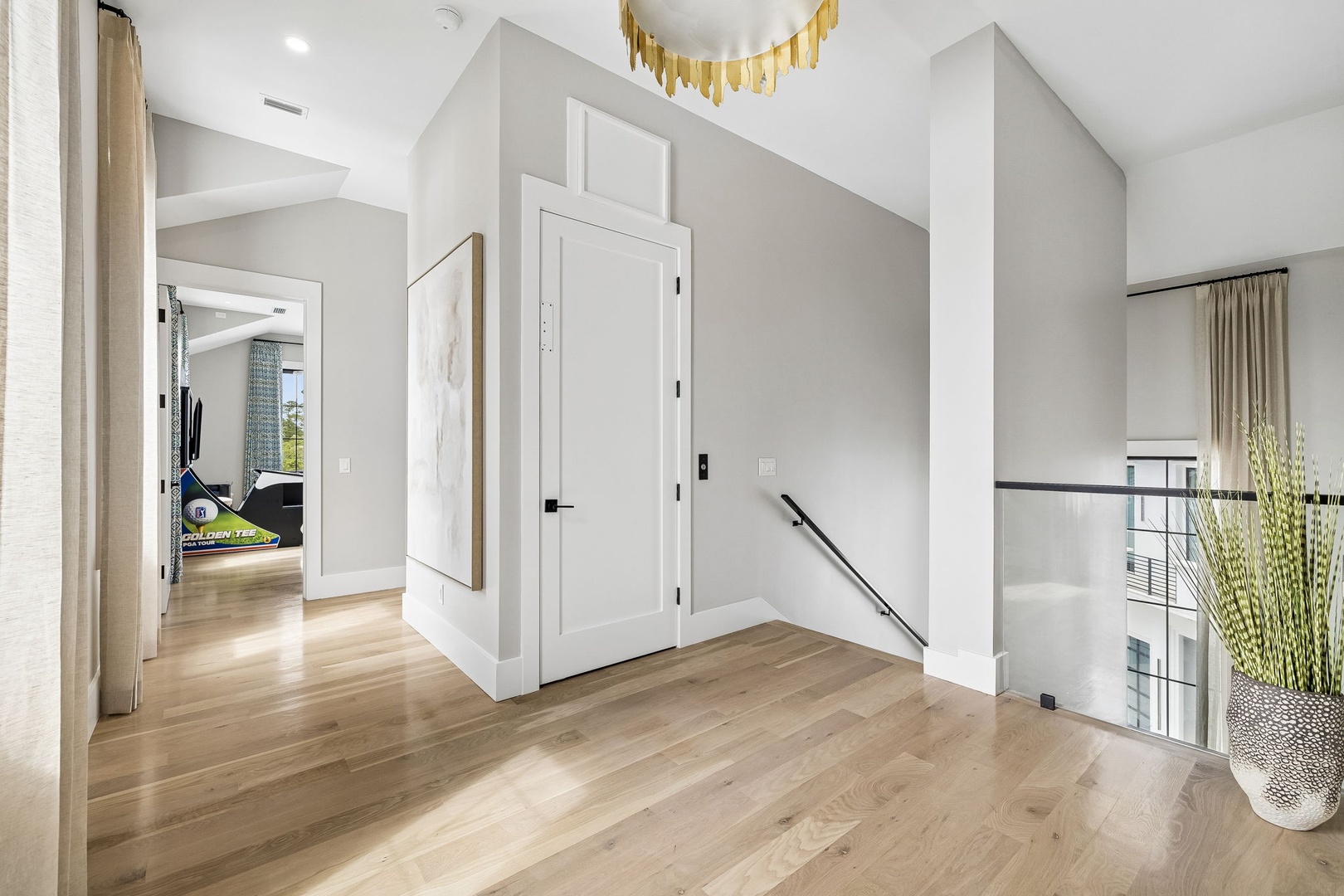 This bright hallway connects your living spaces with clean architectural lines, warm wood floors, and elegant gold accents overhead—creating a welcoming flow throughout your home.