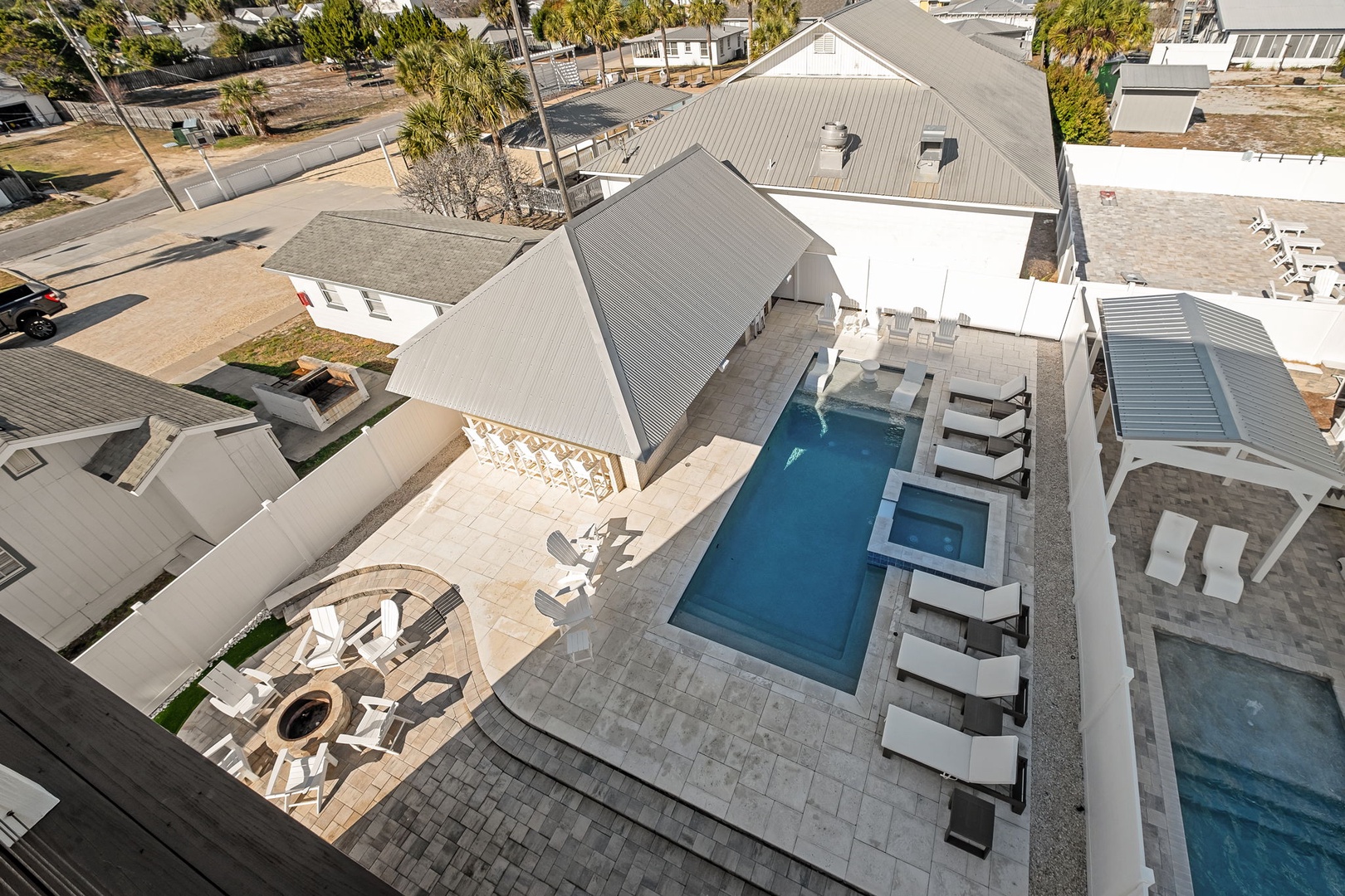 Aerial view showcasing the property's private pool area with hot tub and outdoor lounging spaces in a quiet residential neighborhood.