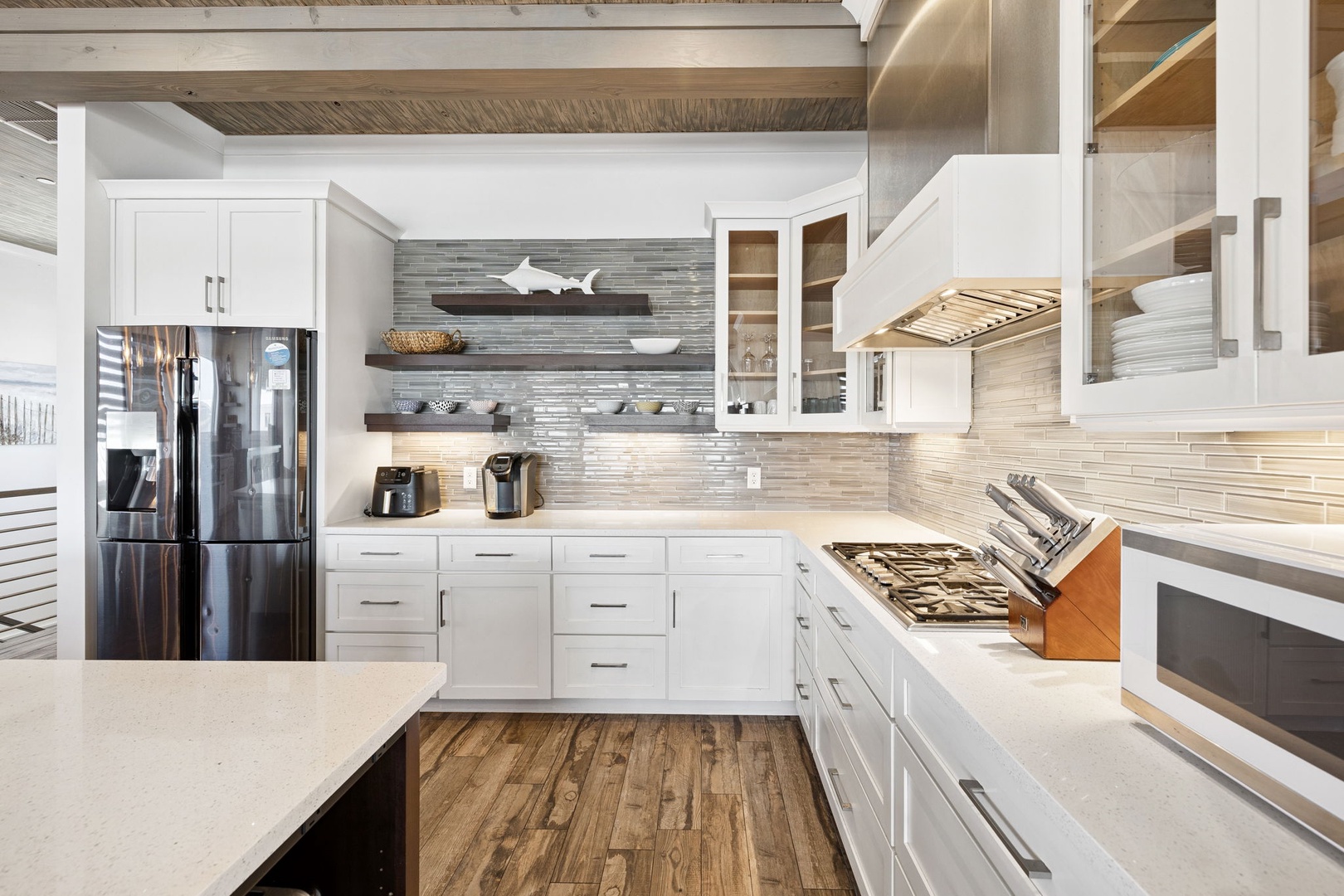 Your dream kitchen awaits with pristine white cabinets, gleaming quartz countertops, and a stunning glass tile backsplash that catches the warm light beautifully.