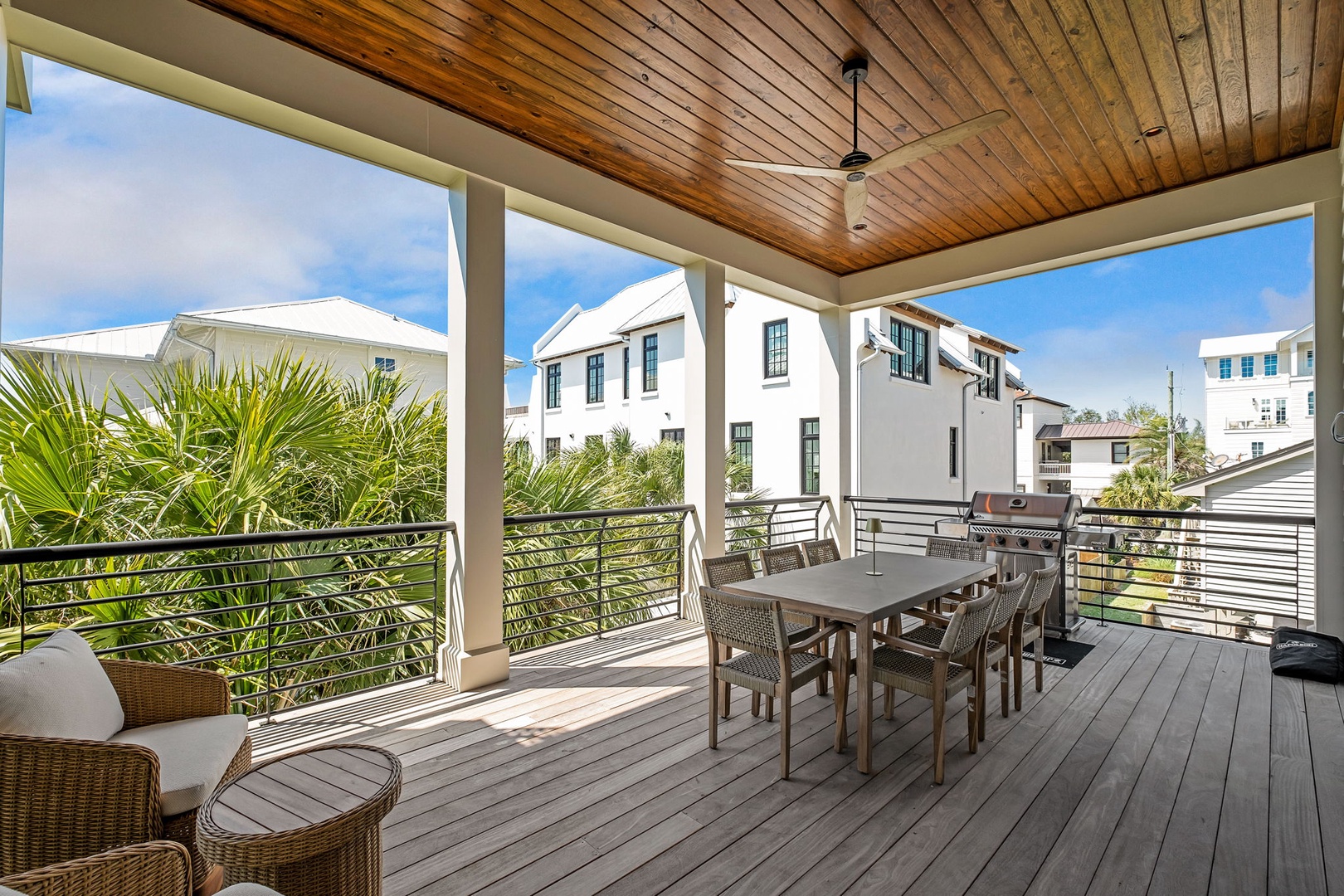 Your covered terrace offers outdoor dining with warm wood ceilings, comfortable seating, and tropical palms framing peaceful neighborhood views.
