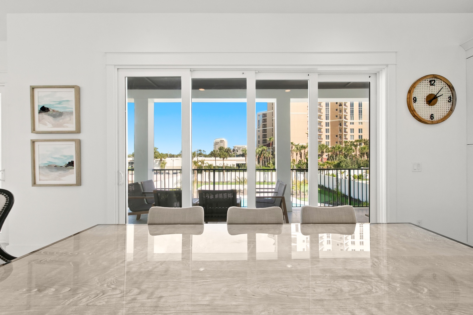 Bright and modern dining space with sleek marble floors and floor-to-ceiling glass doors opening to your private balcony. Step outside and enjoy views of the waterfront and palm-lined surroundings.