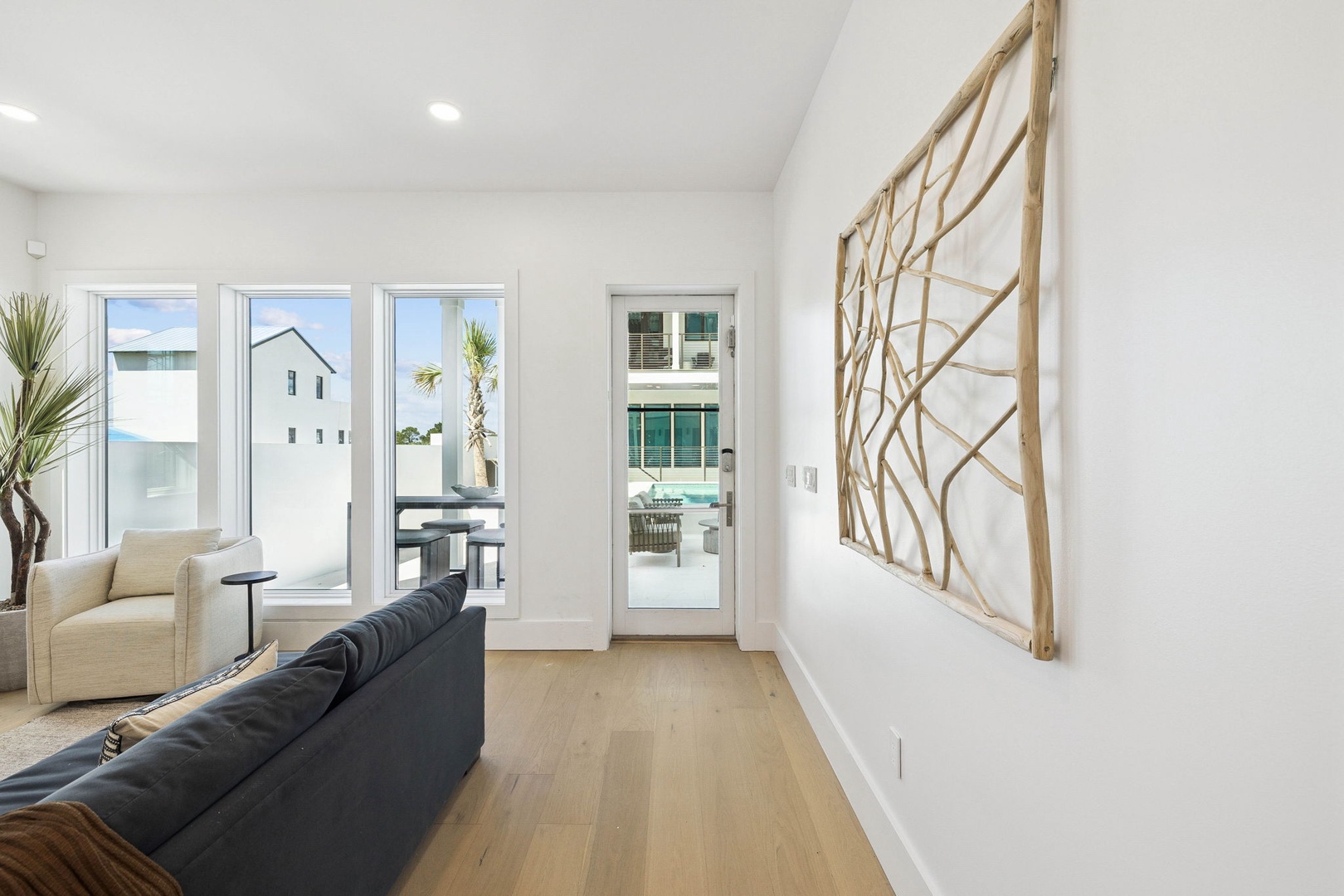 Relax in your bright, contemporary living space where natural light pours in through tall windows and stylish accents create a welcoming coastal ambiance.