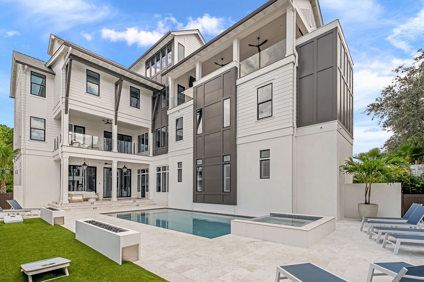 Modern vacation rental property featuring a contemporary architectural design with pool deck, landscaped lawn, and covered outdoor entertaining areas.