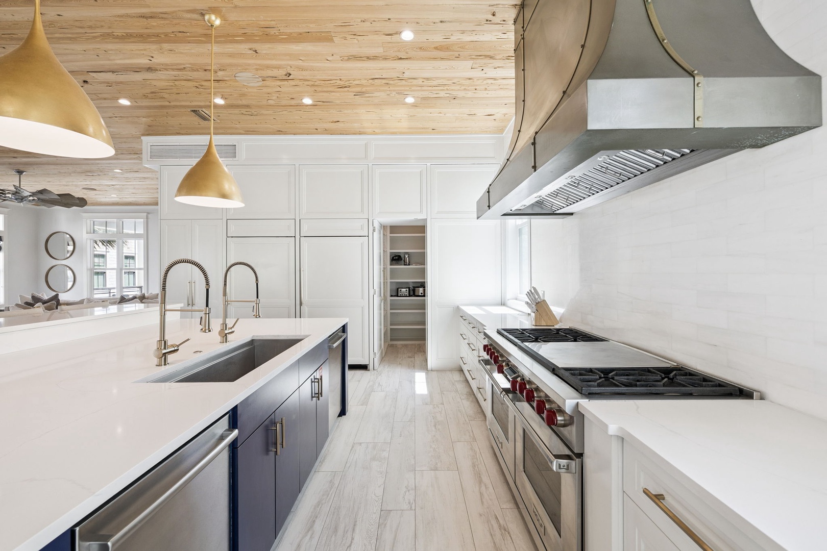 Cook your favorite meals in this stunning modern kitchen with pristine white counters, warm wood ceilings, and gleaming appliances.