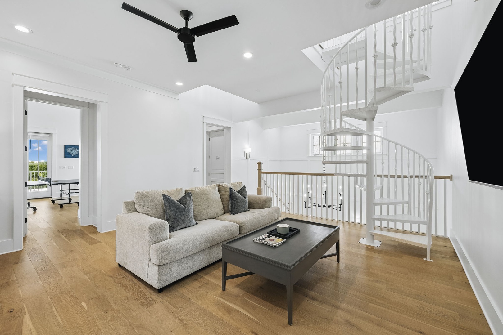 Relax in your bright, open living area with soaring ceilings and elegant spiral staircase leading to the upper level. The plush seating and sunlit rooms invite you to unwind after a day of exploration.
