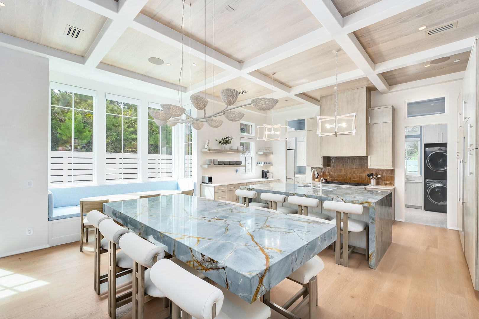 Stunning marble island kitchen with soaring coffered ceilings and abundant natural light. The perfect space to cook, dine, and create memories together.