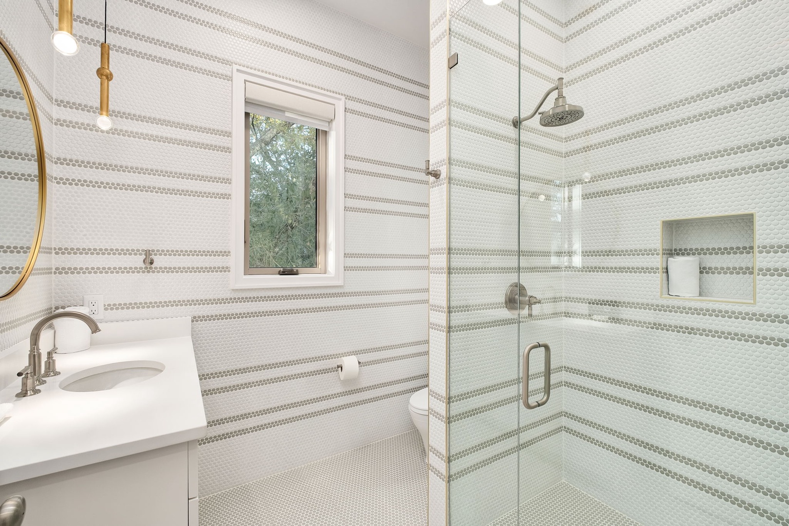Step into your sophisticated bathroom featuring elegant striped tile, a spacious glass shower, and warm brass accents for a luxurious refresh.