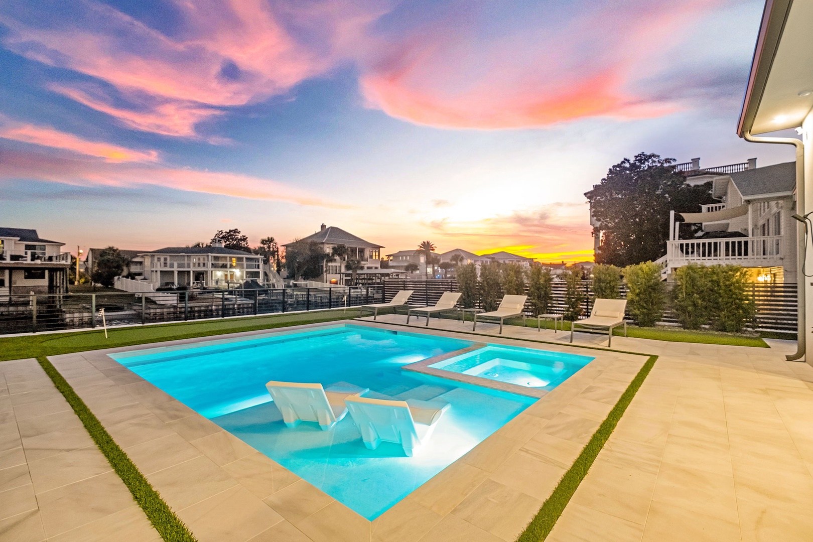 Stunning sunset paints the sky in vibrant pinks and oranges above this elegant residential neighborhood with modern homes.