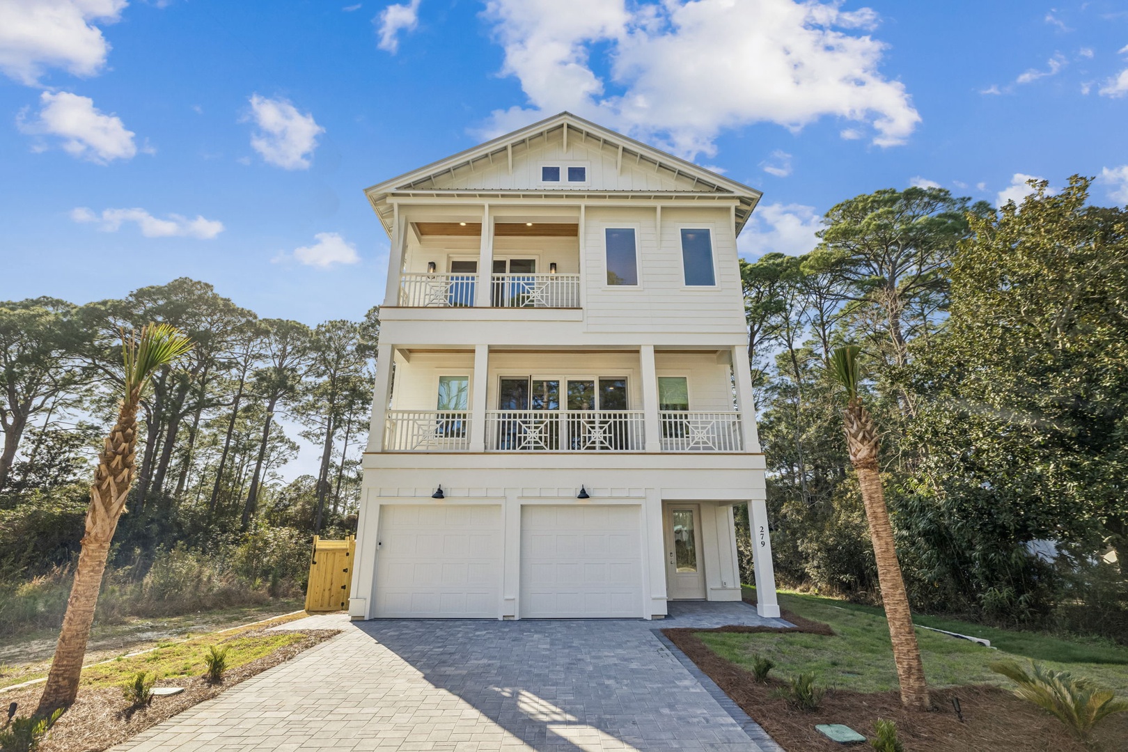Coastal-style three-story home with palm trees and lush landscaping creates a peaceful retreat setting.