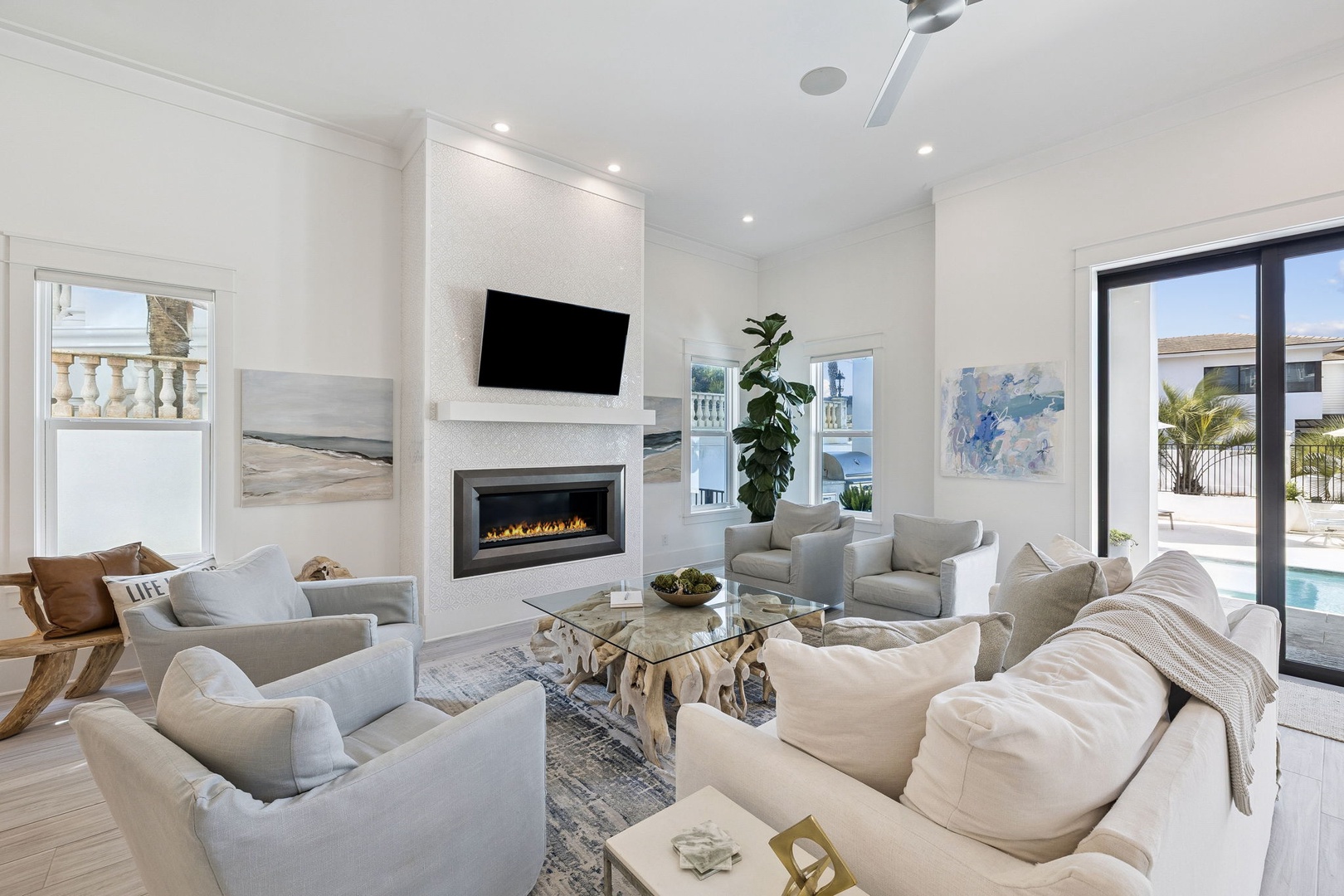 Unwind in your elegant living room featuring plush seating, a cozy fireplace, and bright spaces that flow seamlessly to your private pool.