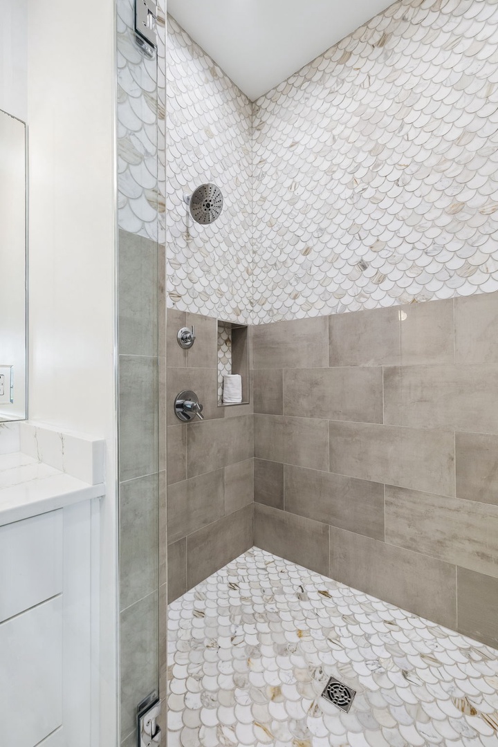 Your private sanctuary awaits—step into a beautifully tiled walk-in shower with elegant scalloped accents and soothing neutral tones designed for pure relaxation.