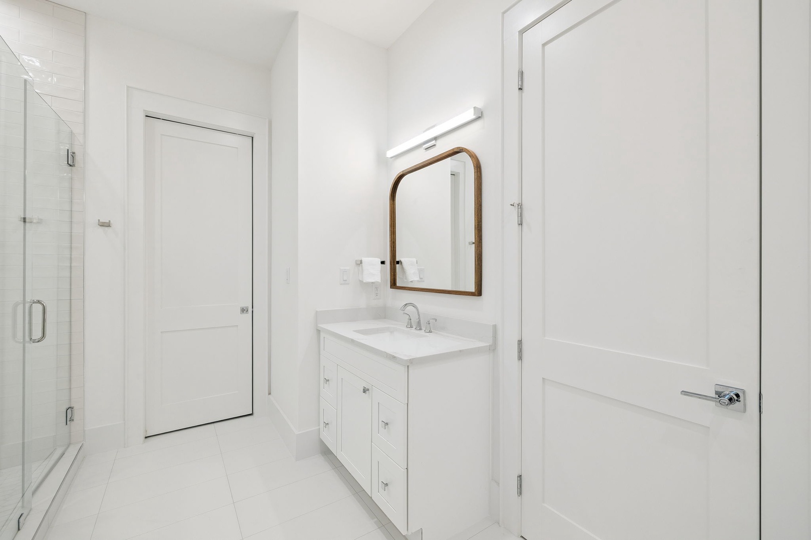 Step into your pristine white bathroom featuring a spacious vanity, elegant mirror, and glass shower—perfect for refreshing after your adventures.