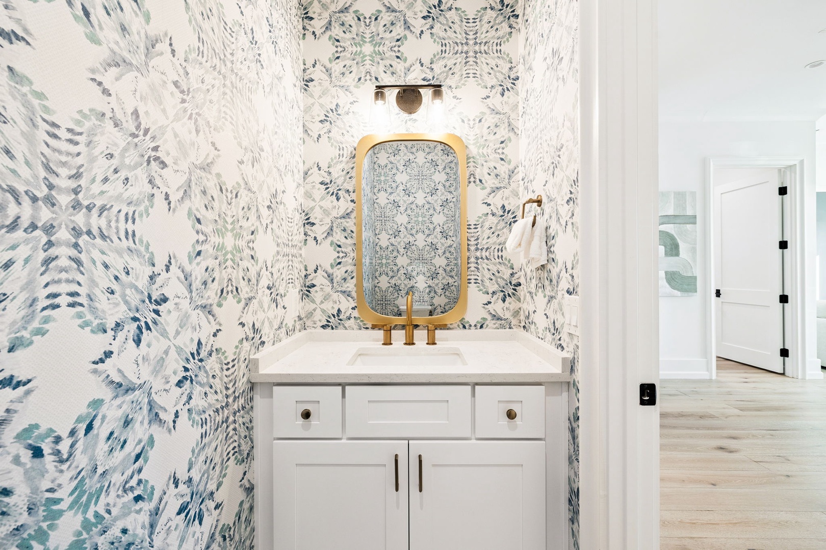 Step into your private powder room featuring stunning botanical wallpaper and elegant brass fixtures that create a luxurious retreat.