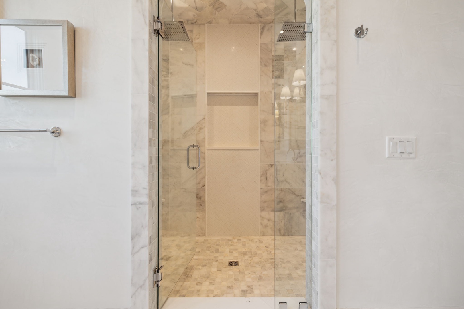 Enjoy the luxurious walk-in shower with its elegant marble tile, dual rainfall showerheads, and sleek glass enclosure—perfect for refreshing after a day of exploring.