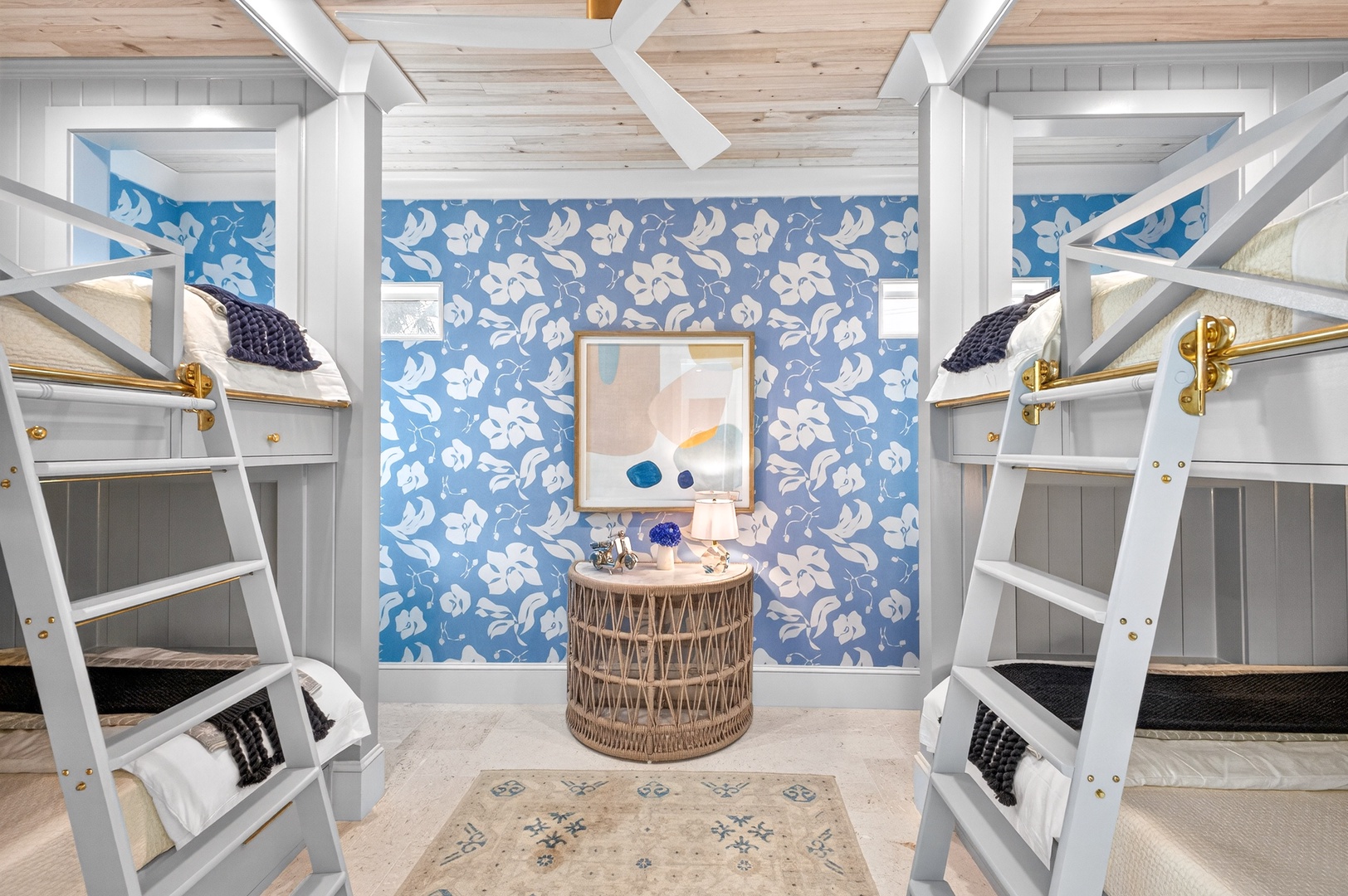 Your coastal retreat features charming bunk beds with golden fixtures, perfect for family gatherings under exposed beams.