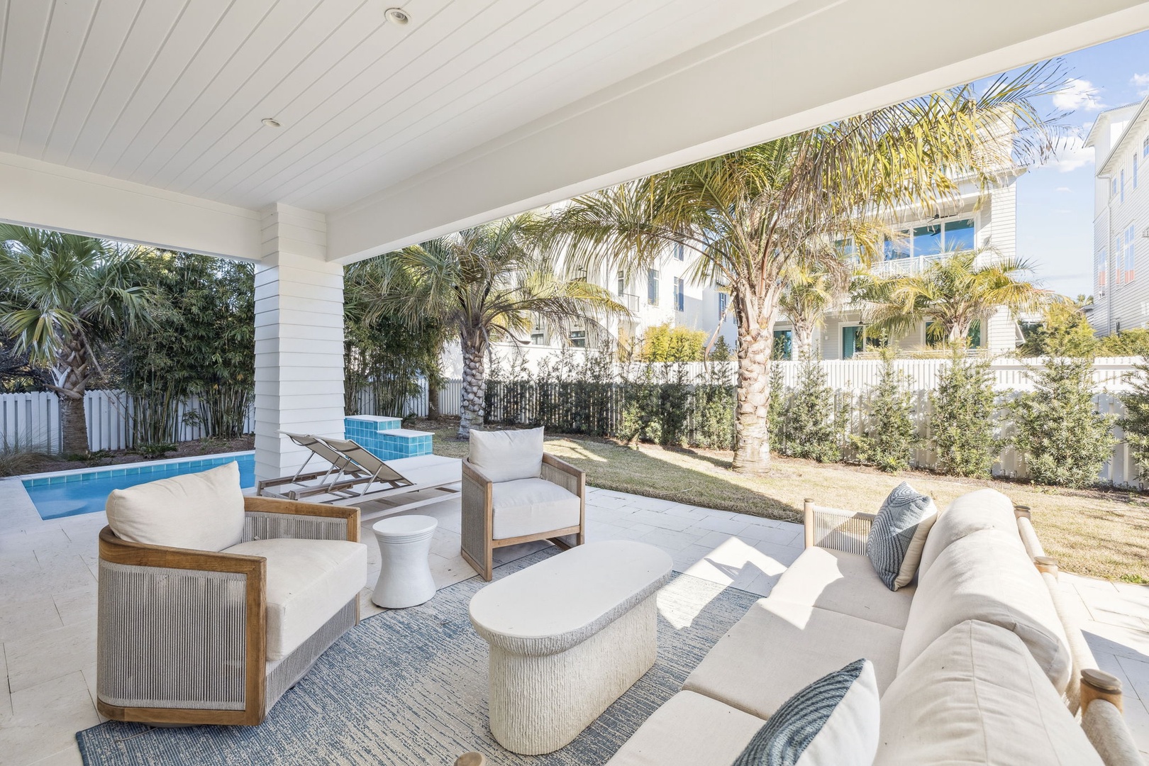 Unwind in your covered outdoor oasis with plush seating, pool views, and tropical palms creating the perfect paradise retreat.