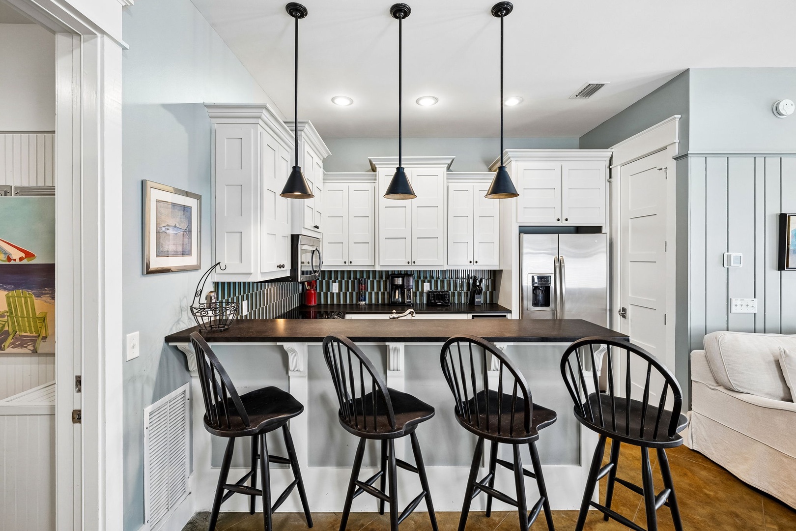 Gather at the breakfast bar in your coastal-style kitchen, complete with modern appliances and chic pendant lighting—perfect for morning coffee or casual meals together.
