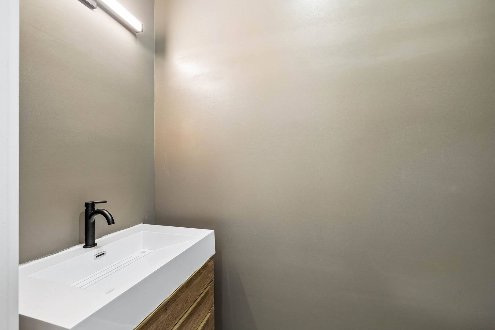 Freshen up in your sleek modern bathroom with a stylish white sink and warm wood vanity—minimalist design that feels clean and welcoming.