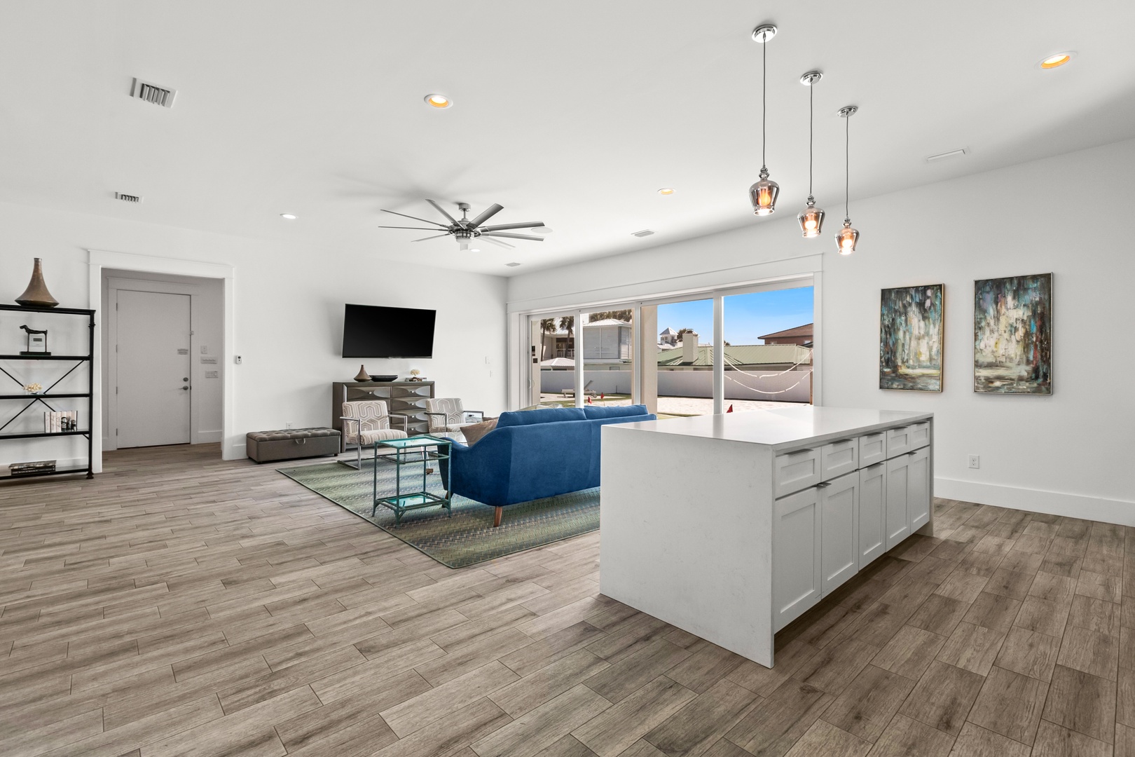 Step into your bright, open living space where a plush blue sofa invites you to unwind. Natural light pours through patio doors, blending the kitchen and living areas into one seamless retreat where you'll love spending time.