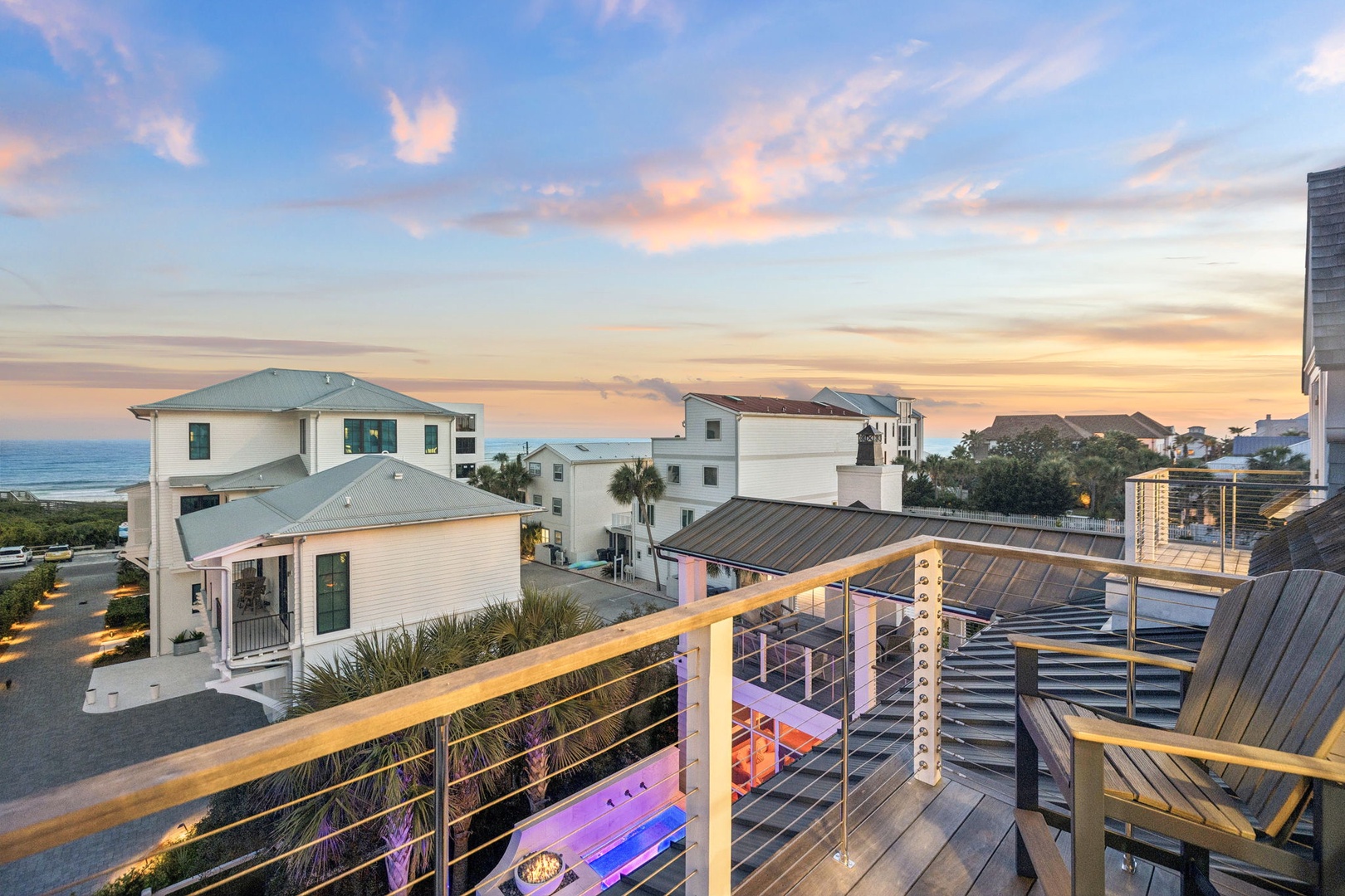 A stunning coastal neighborhood at sunset, featuring beach cottages and modern architecture with the ocean visible in the distance—part of the property's picturesque surroundings.