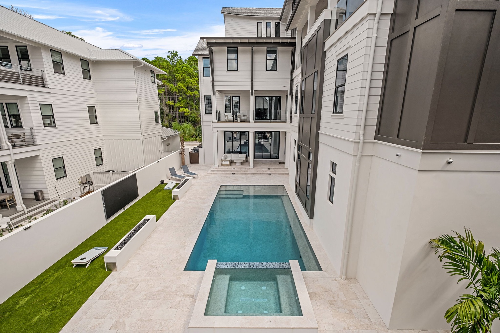 An elevated view showcases the property's sleek courtyard pool and spa, framed by modern architecture and neighboring homes.
