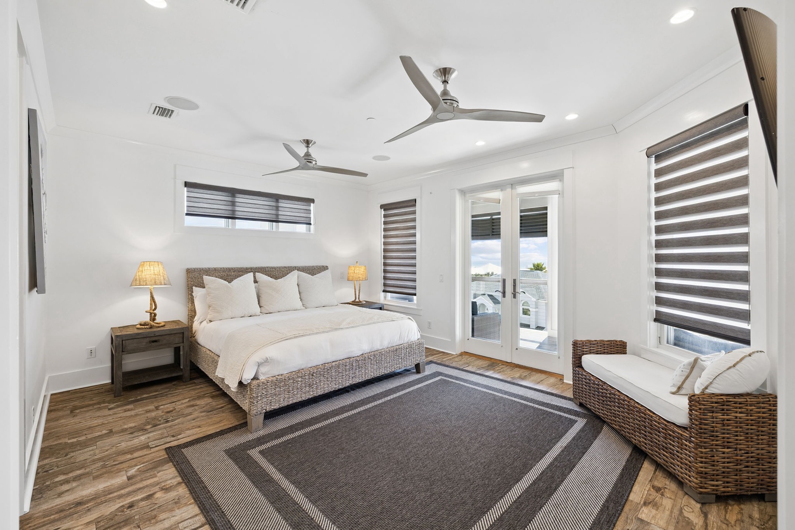 Sink into crisp linens and natural textures in your serene bedroom retreat, complete with private balcony access and ocean breezes from ceiling fans.