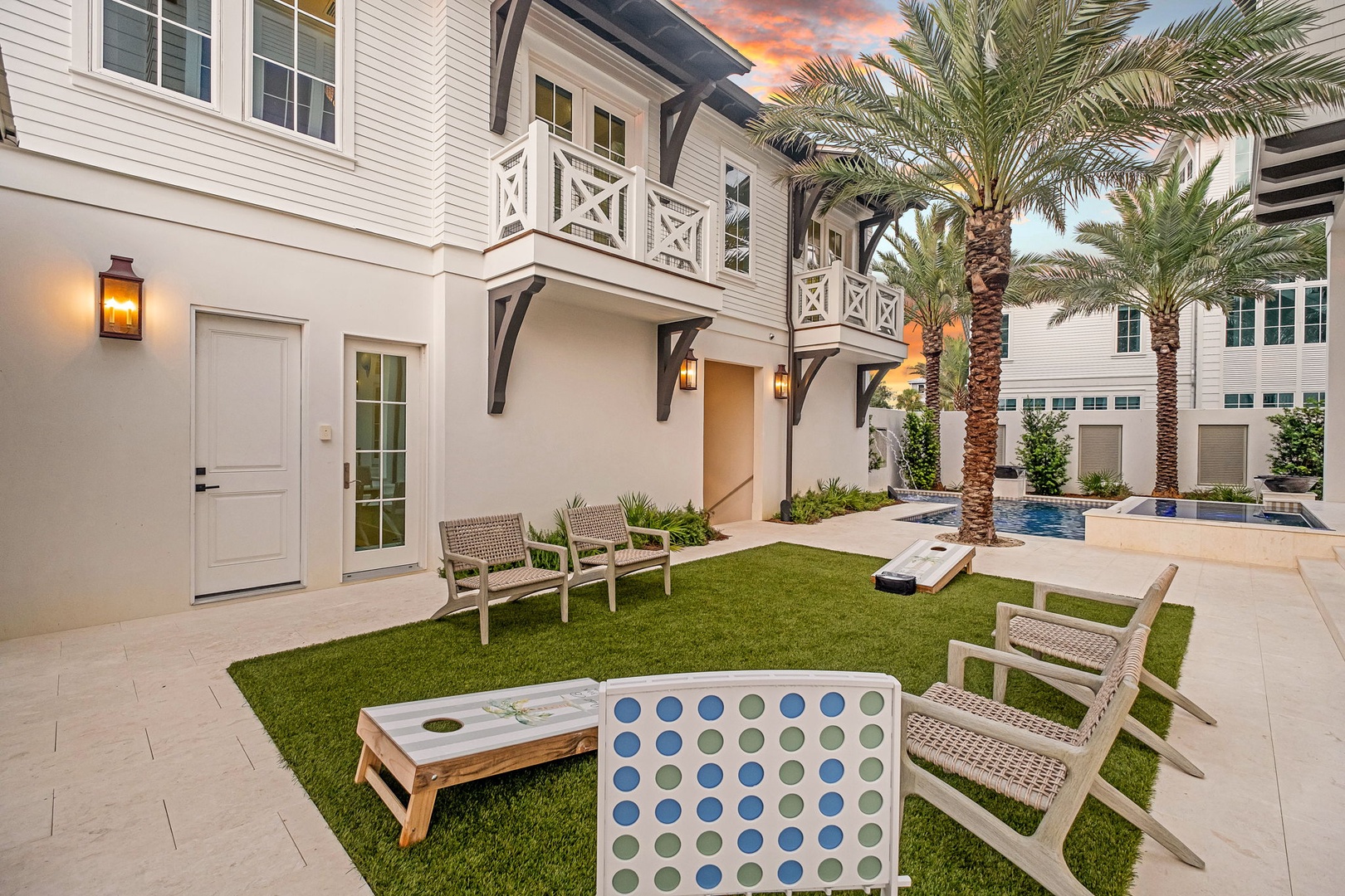 A tropical courtyard awaits with lush grass, swaying palms, and poolside lounging—your private oasis for unwinding under vibrant sunset skies after a day of exploring.