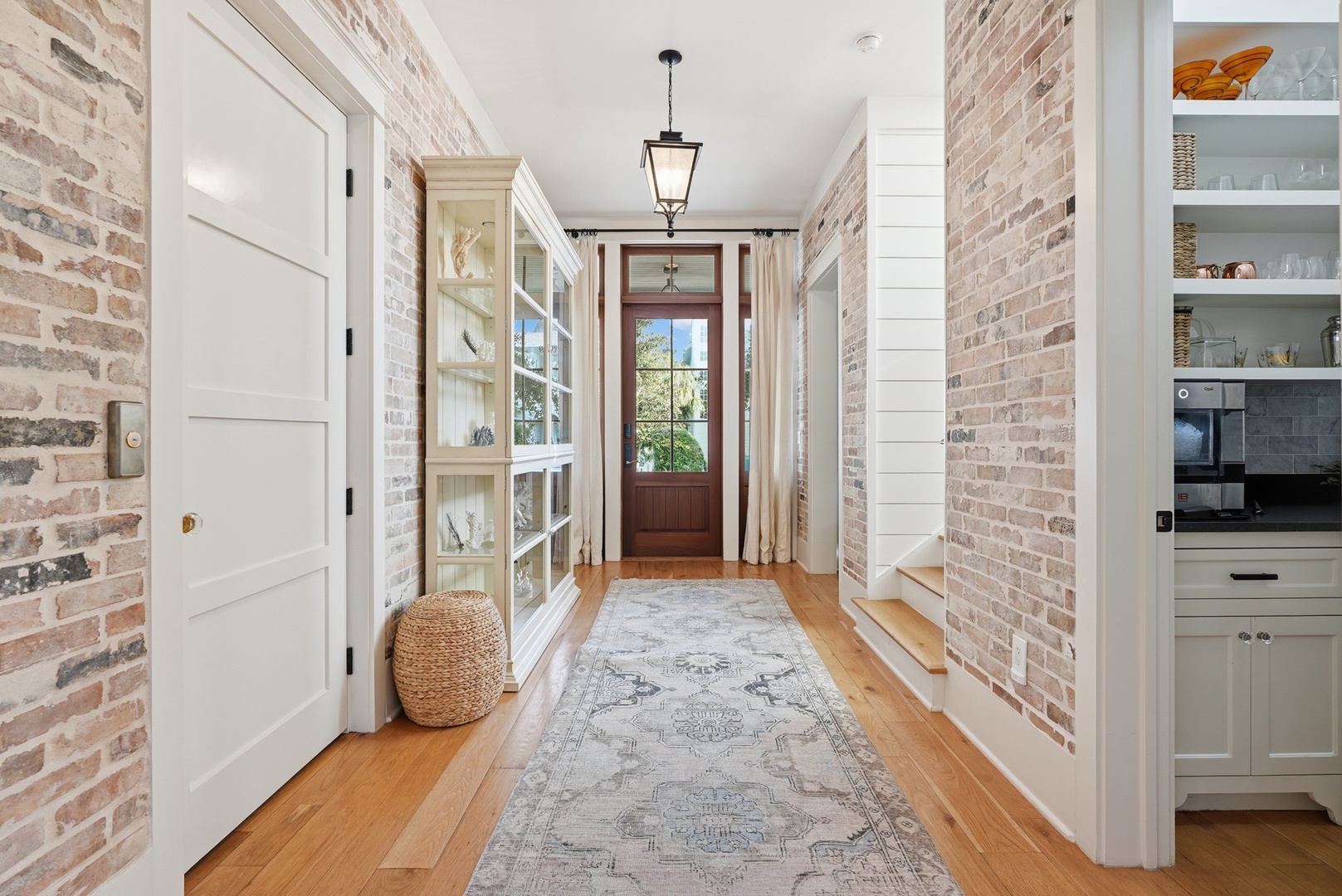 This charming brick-lined entry welcomes you with rustic warmth and inviting modern farmhouse style, blending exposed brick, elegant lighting, and thoughtfully curated decor for a cozy first impression.