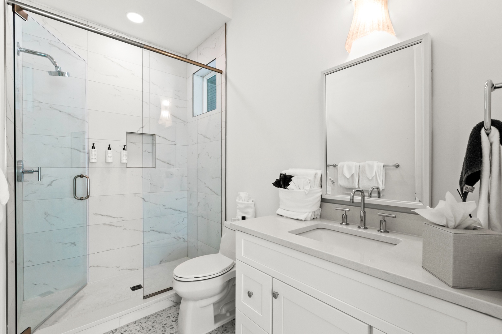 Step into your pristine, modern bathroom featuring elegant marble-look tile, a spacious walk-in shower, and fresh white towels waiting just for you.
