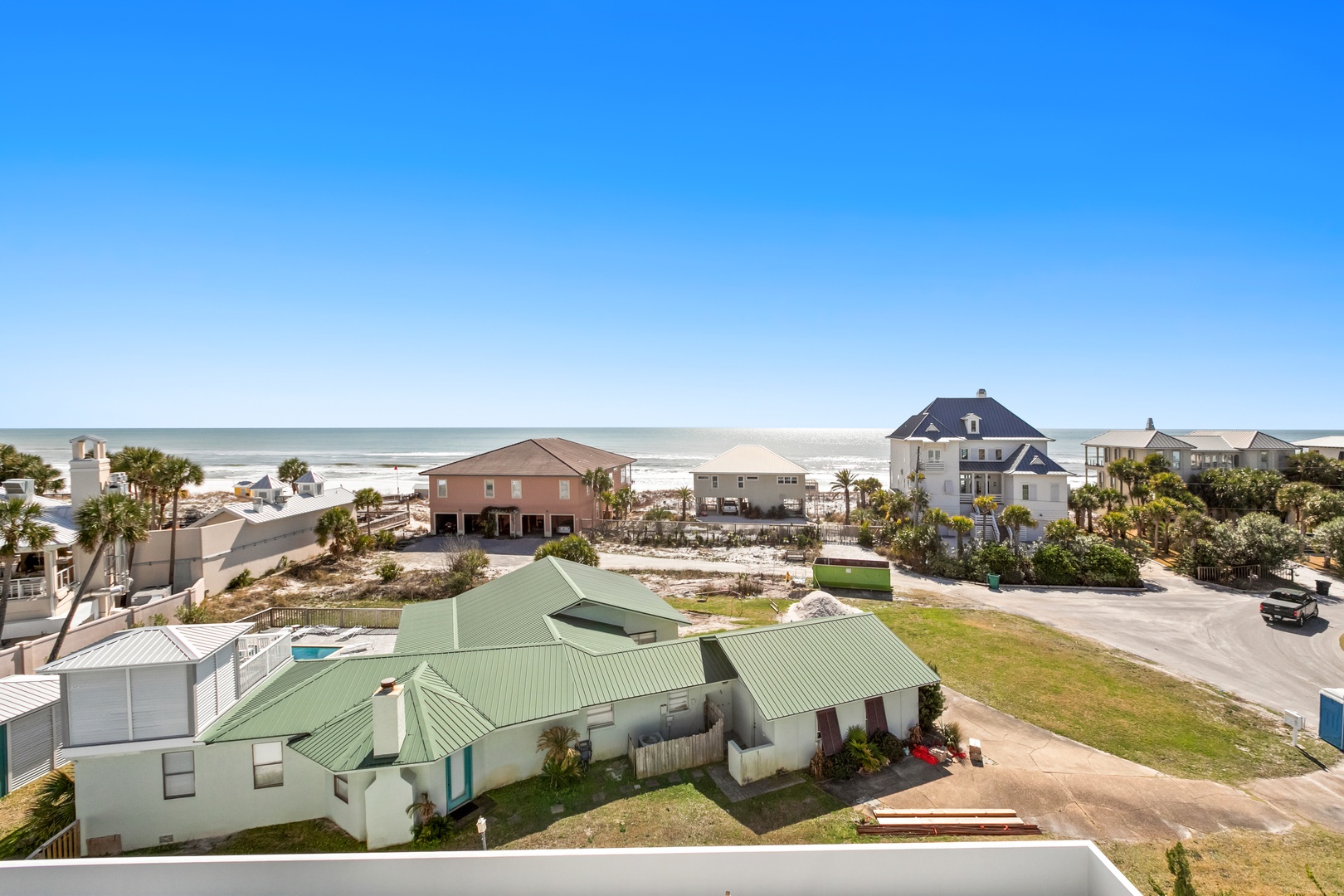 Beachfront property nestled among coastal homes with direct ocean access and sweeping views of the sandy shoreline and neighboring residences.