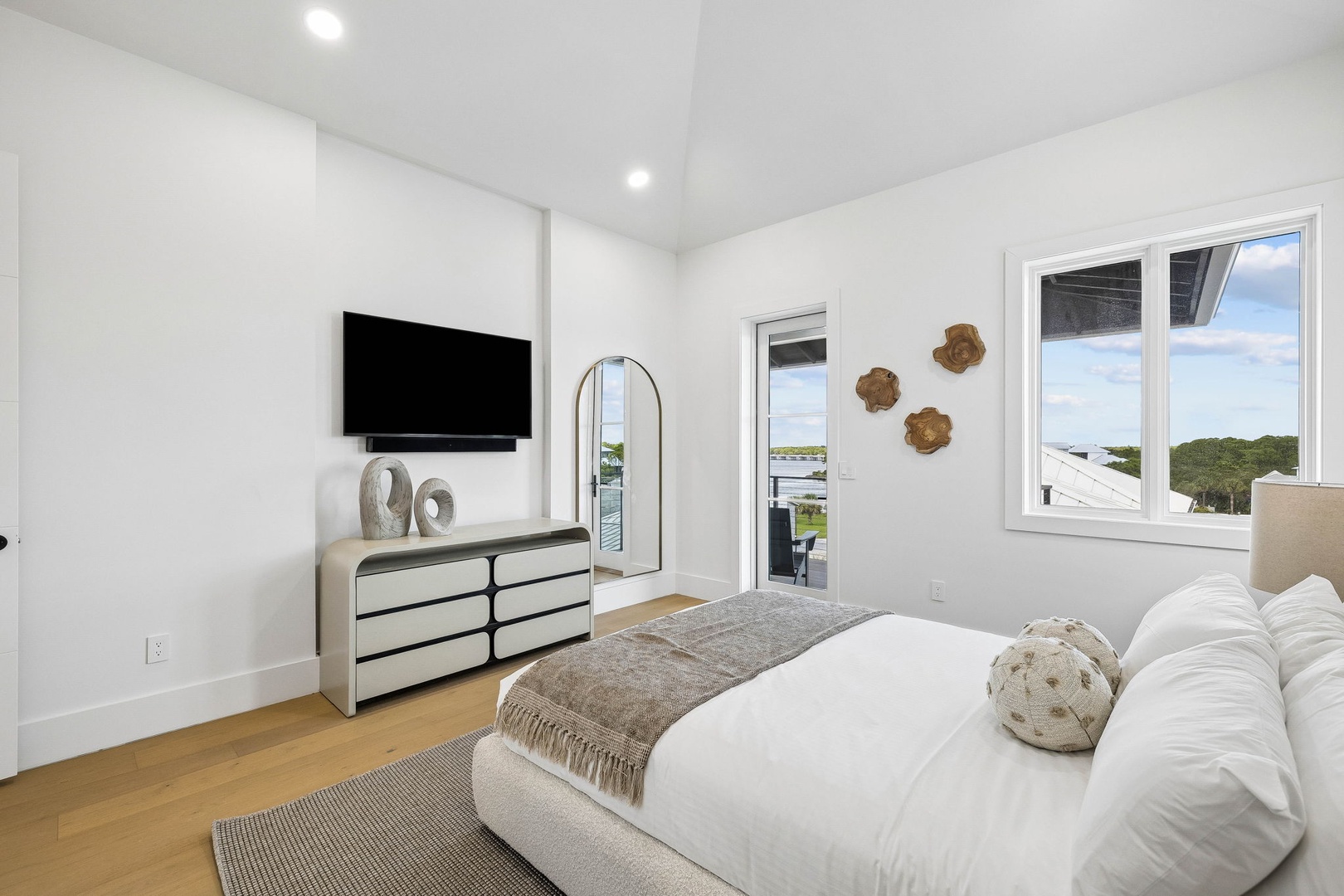 Your serene coastal bedroom awaits with a plush bed, calming neutral palette, and natural views framed by expansive windows. Step onto your private balcony to soak in the peaceful waterfront scenery and breathe in the fresh air.