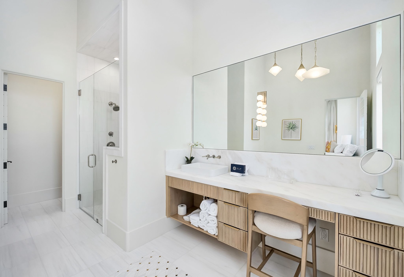 Step into your serene spa-like bathroom, where a spacious walk-in shower and elegant marble vanity await. Natural light fills the room, highlighting warm wood accents and plush towels—perfect for your morning refresh.