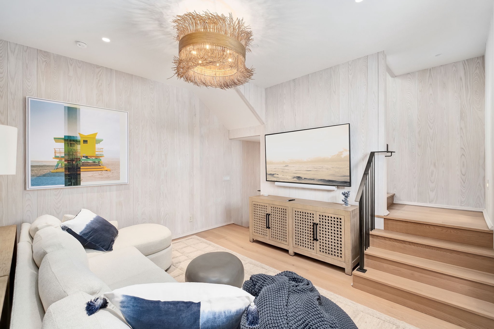 Unwind in your airy living space with coastal-inspired decor, soft neutral tones, and a striking woven pendant casting warm light overhead—the perfect retreat after a day at the beach.